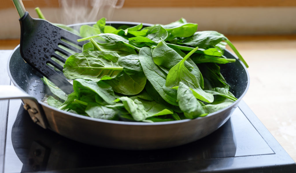 Sautéing fresh spinach in a pan