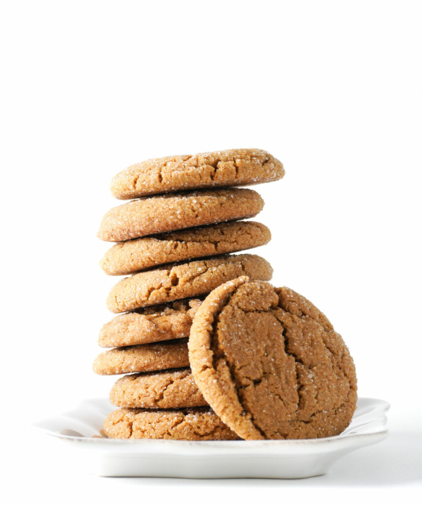 A gingerbread cookie leans on a stack on cookies on a white plate isolated on a white background; copy space